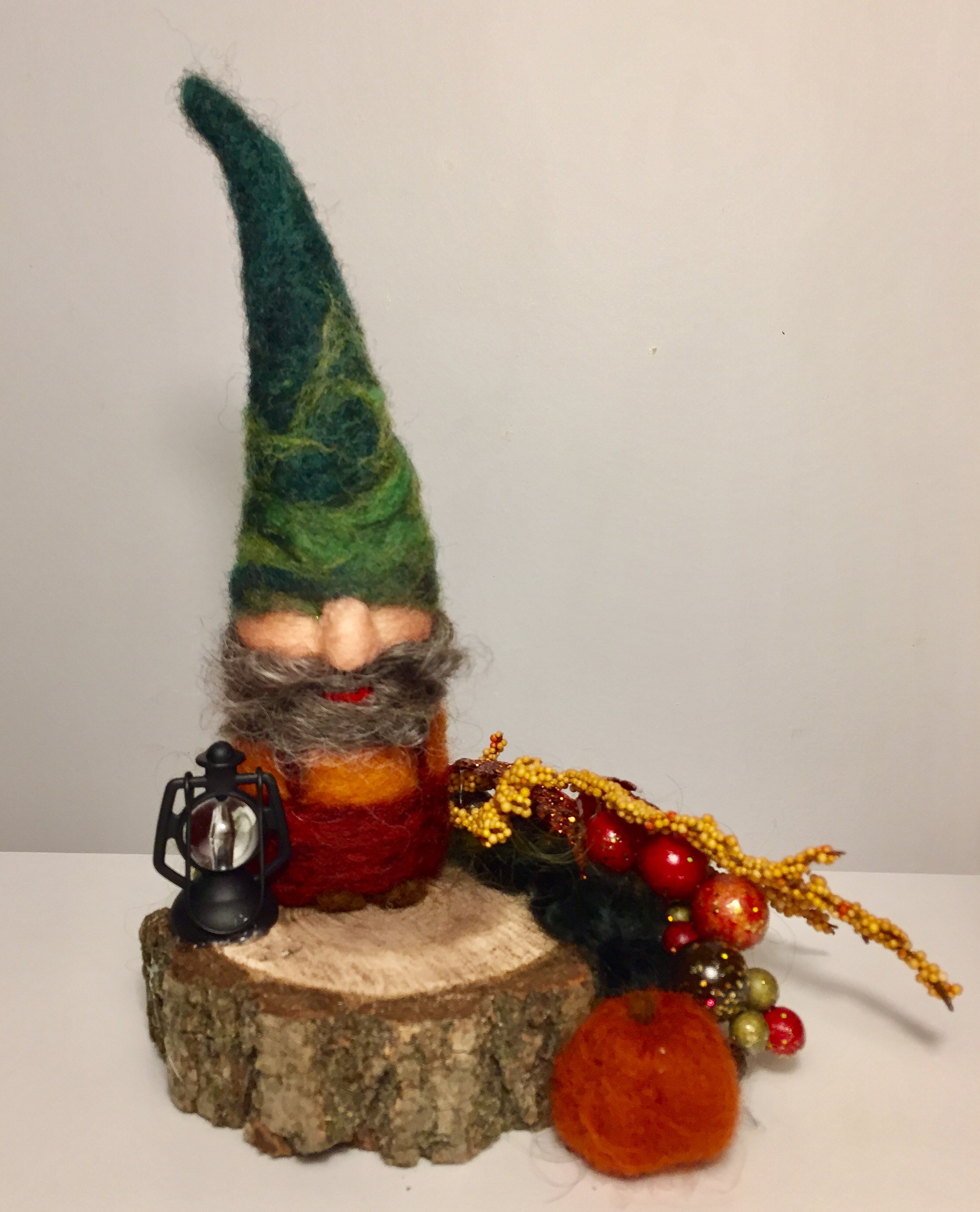 felted gnome on a log with a tall green pointed hat